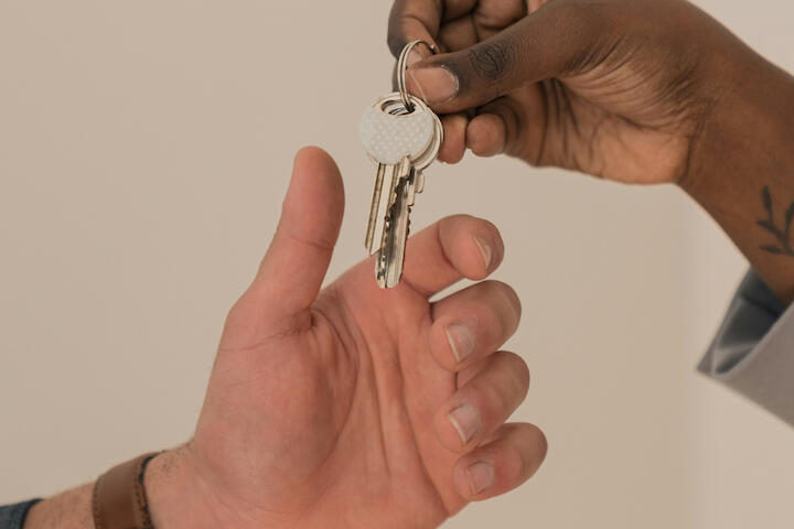 Eine Hand reicht einer anderen Hand einen Schlüssel