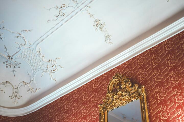 Ausschnitt einer Stuckverzierung an der Decke und eines goldenen Spiegels im Rokoko-Stil
