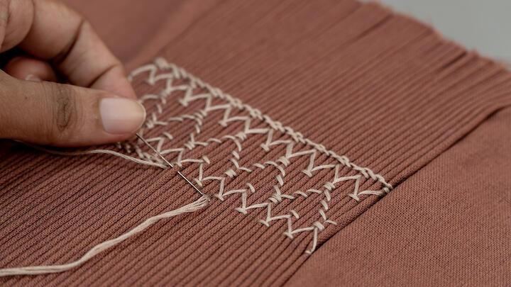 Eine Smock-Stickerei auf rostfarbenen Stoff