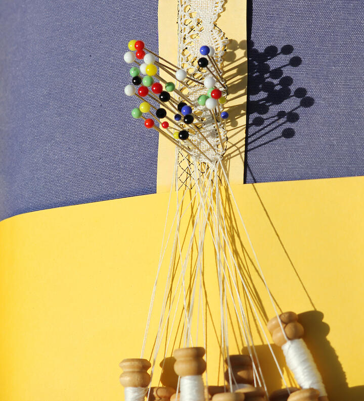 Ein dünne Spitzenborte wird geklöppelt.