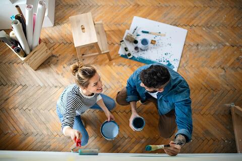 Eine Frau und ein Mann streichen eine Wand