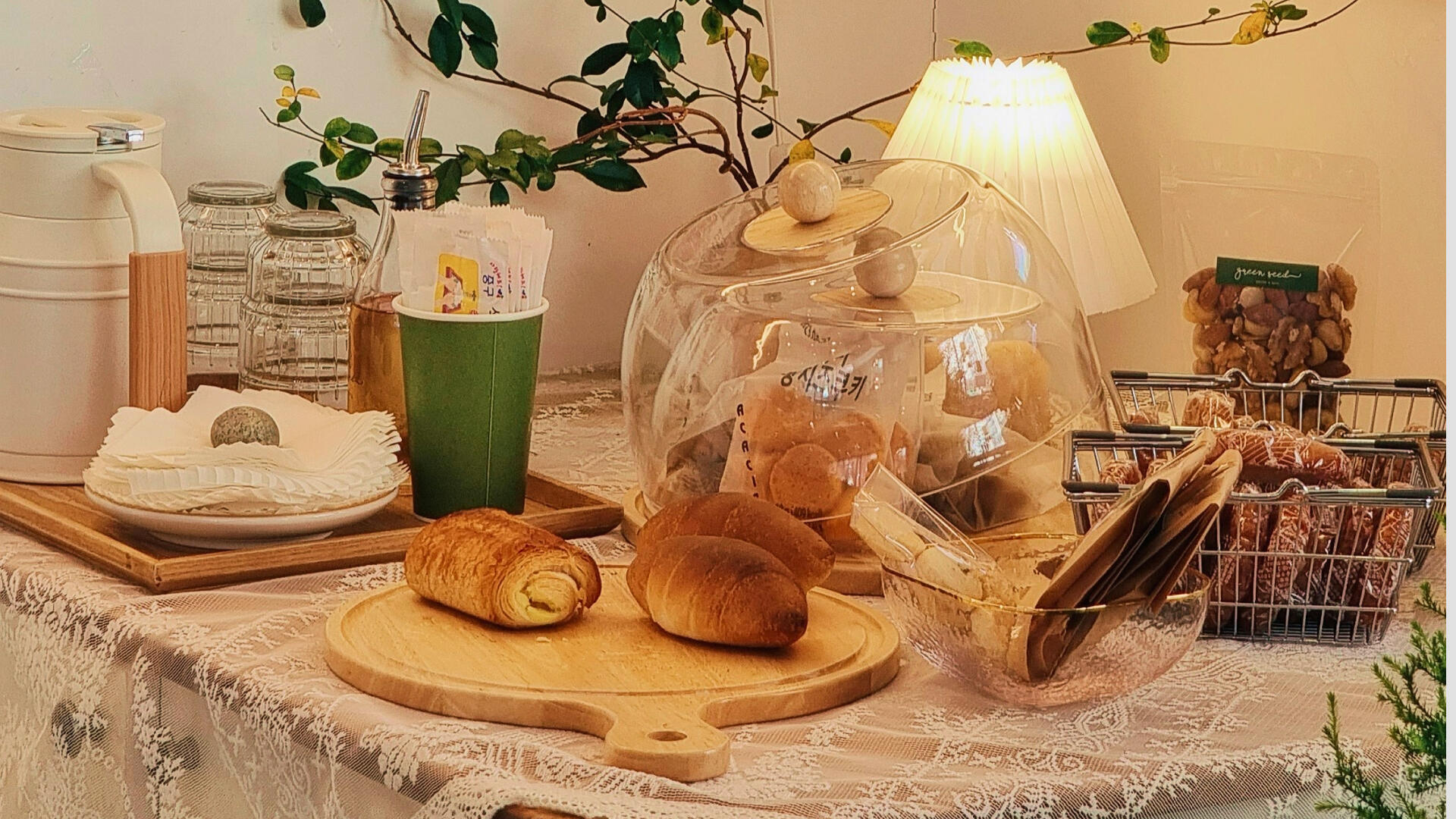 Auf einem Tisch steht eine Kanne, Gläser und es leigen dort einige Croissants. Alle leuchtet in einem warmen Licht.