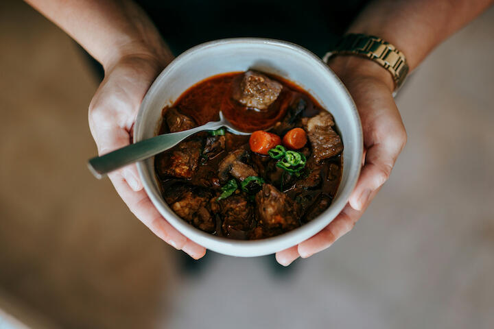 Aufsicht auf eine Schale mit Eintopf, gehalten von zwei Händen.