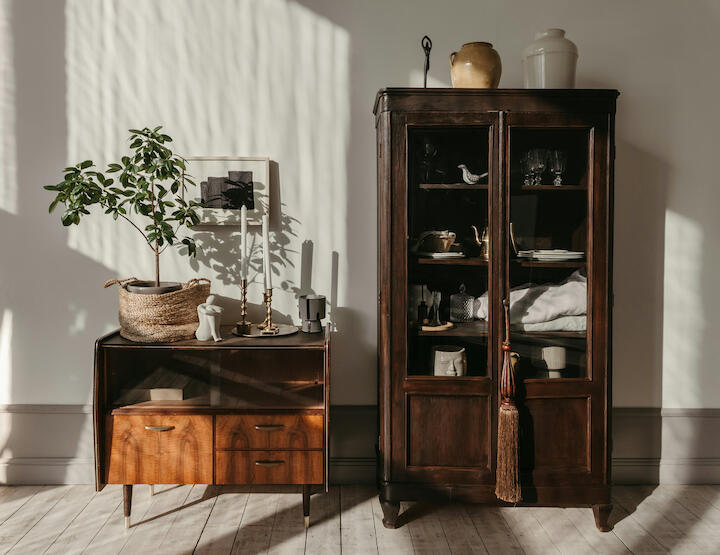 Eine Mid-Century Kommode steht neben einem alten Vitrinenschrank.