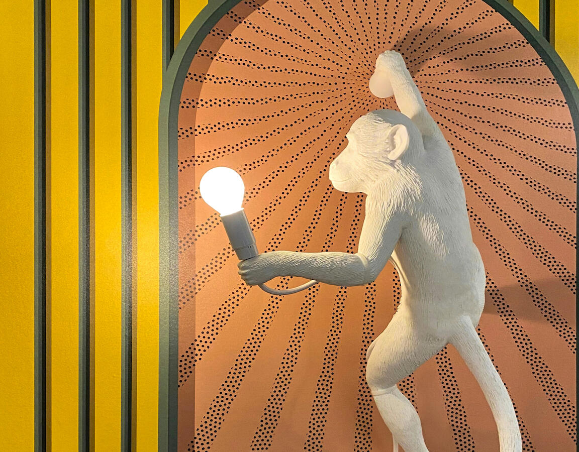 Eine Lampe in Form eines Affen an einer gelben Wand