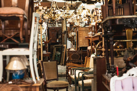 Ein Blick in eine Lagerhalle voller schöner Flohmarktfundstücke. Kornleuchter, Stühle, Spiegel etc.