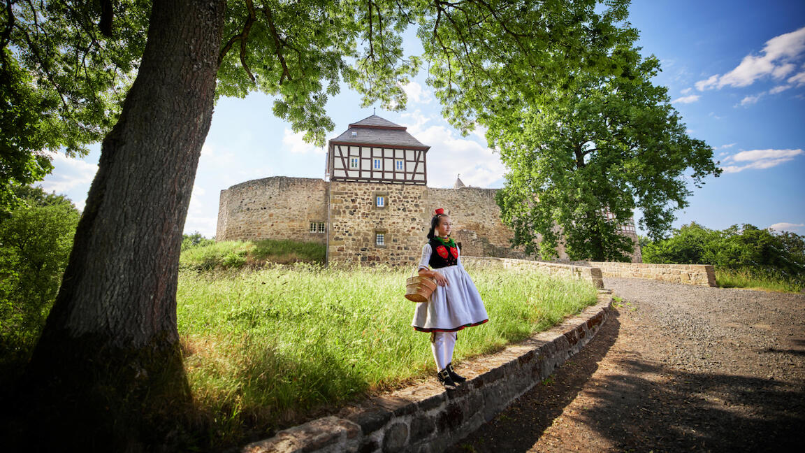 Ein Mädchen in Rotkäppchen-Kostüm vor einer Burg