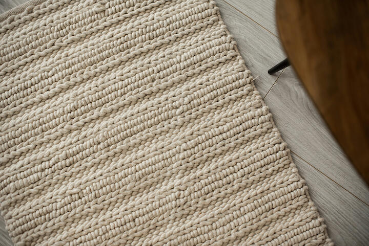 Aufsicht auf einen wollenden Teppich in Off-White mit geflochtenem Muster.
