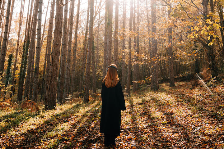 Eine Frau steht im herbstlichen Wald.