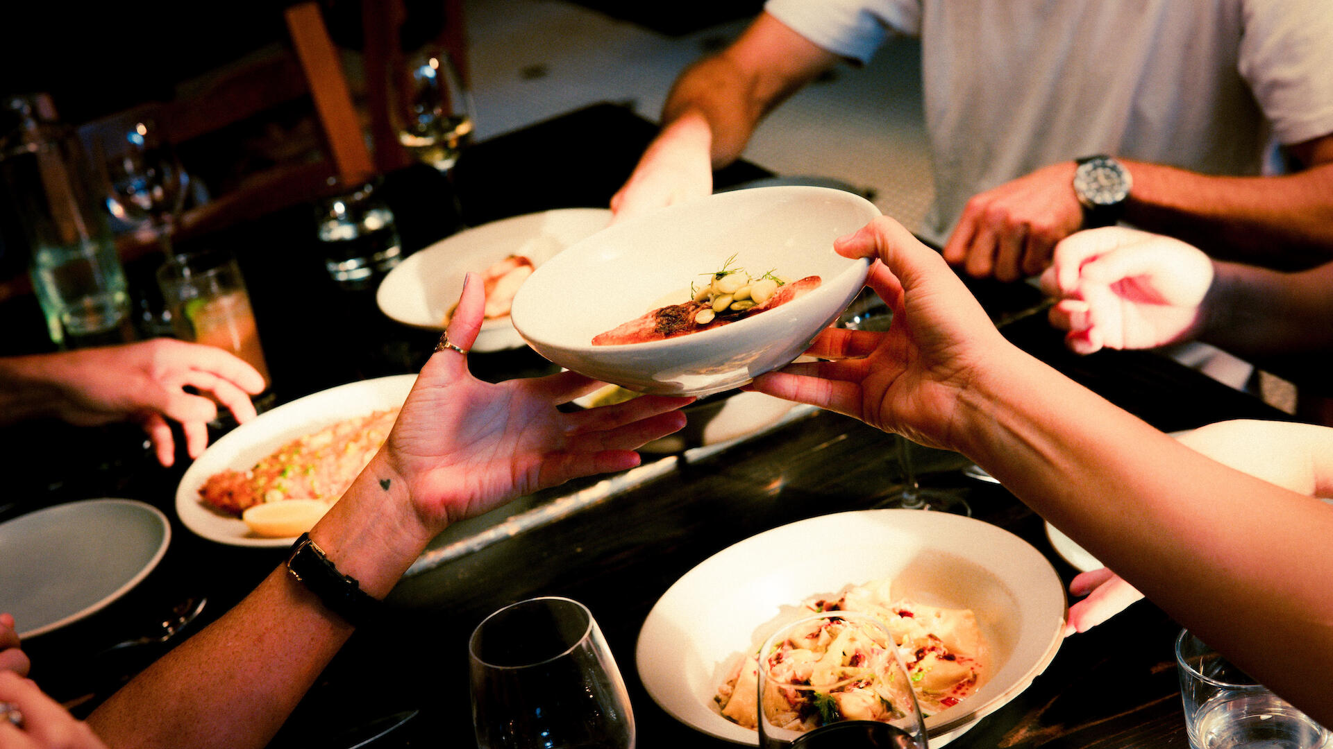Menschen essen am Tisch und geben sich Essen rüber
