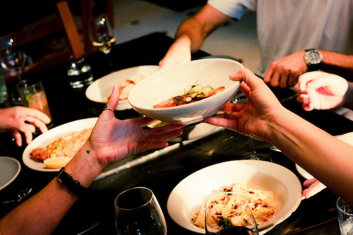 Menschen essen am Tisch und geben sich Essen rüber